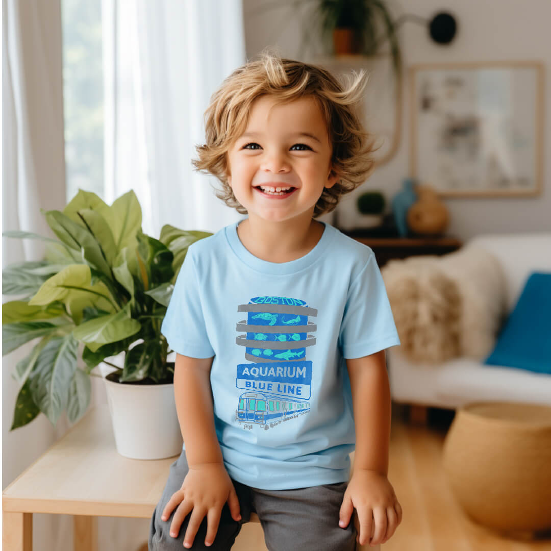Toddler boy wearing light blue Boston Aquarium and Blue Line Train T-Shirt
